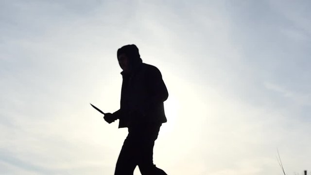 Manjack with knife silhouette slow motion outdoors