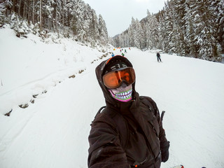 Handsome snowboarder at ski slope taking selfie.
