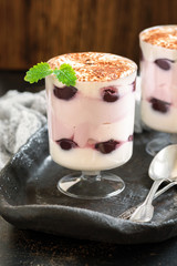 Curd berry dessert in a glass on a ceramic rustic tray. Dessert of cream and cherry layers.