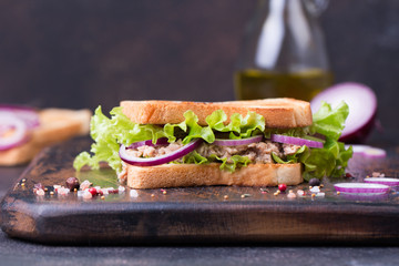 Tuna fish sandwich with onion, lettuce and olive oil on a wooden board.