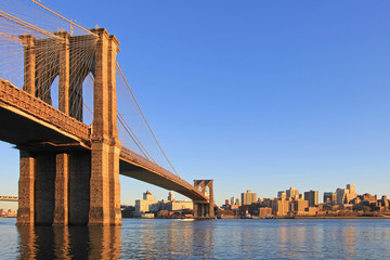 Brooklyn Bridge over East River with view of New York City Lower Manhattan, waterfront at twilight, USA