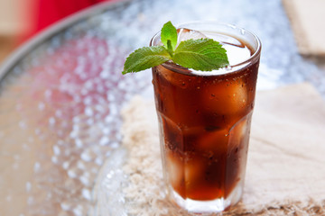 Cold summer drink in glass with ice and mint on the table