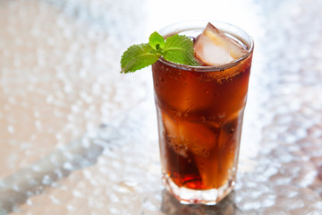 Cold summer drink in glass with ice and mint on the table