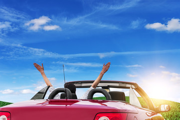 Young woman in a car with a convertible on the road to the nature on a sunny day.