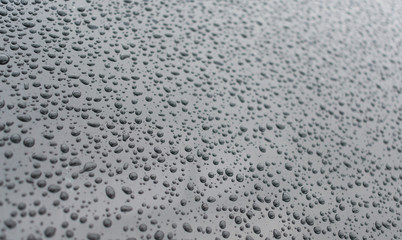Water drops on a dark silver surface.