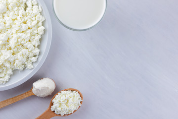 Assorted dairy products on a white board, cottage cheese, cream and soft cheese on a white background, milk in a glass, soft cheese for sandwiches, wooden cutlery, copy space