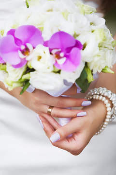 Beautiful purple manicure of young bride. Focus at finger with golden ring. Shallow depth of field. Vertical color photography.