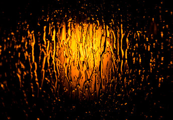 Orange light behind the glass with raindrops on it, artistic representation of the hope