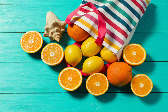 Summer fun time. Fruits on blue wooden background. Orange, lemon fruit in bag on table. Top view and mock up. Copy space. Sea shell. Selective focus