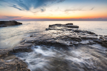 Fototapeta premium Enjoying the colorful sunset on a beach with rocks on the Adriatic Sea coast Istria Croatia