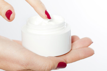 Middle age woman putting pomade on hand from the bottle isolated on white background. Spa and anti aging concept. Wrinkles. Red manicure. Copy space. Selective focus