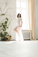 Young beautiful bride posing near the big window