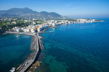 Scenic overlook view of the waterfront village of Ischia Ponte with the volcanic mountains towering above the horizon on the Mediterranean island of Ischia, Italy