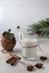 Shell of coconut and coconut milk in glass with cinnamon on wooden table.