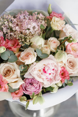 bouquet of beautiful flowers with peony on gray table. Floristry concept. Spring colors. the work of the florist at a flower shop. Vertical photo