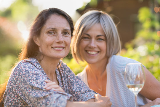  Portrait of two beautiful women in their forties. moment of complicity for female friends posing for the terrace photo in front of a glass of wine.
