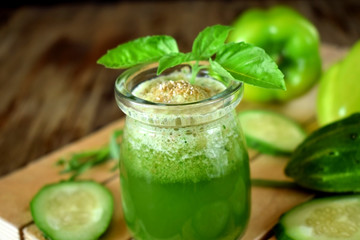 Green cocktail in a glass jar sprinkled with brans decorated with basil on wooden background