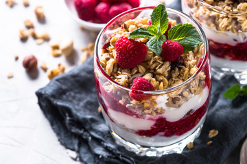 Yogurt parfafait with granola and raspberries in glass.