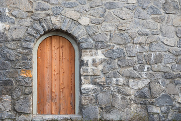 rustikale graue Steinmauer mit Bogentüre aus Holz