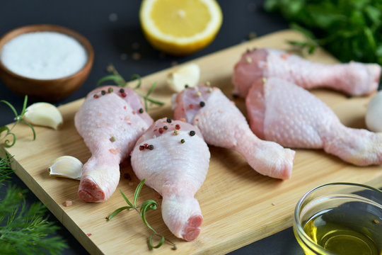 Raw Chicken Legs with Green Herbs and Spices Pepper on Wooden Cutting Board Food ingredient Salt Rosemary Lemon Oil Preparation Lifestyle Healthy Concept Black Background