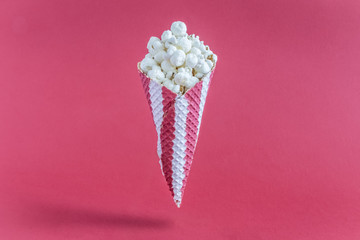 Popcorn in cone on red background minimalistic concept.