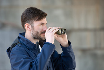 man detective watches binoculars on a city street