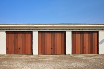 Row of garages with closed gates on a sunny day.