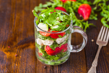 Fresh vegetable strawberry salad in glass jar on natural rustic desk.