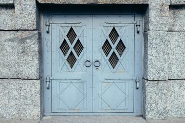 Grey old metal door with stone wall around