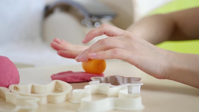 Children's creativity. The girl's hands form the shapes of the dough on the table.