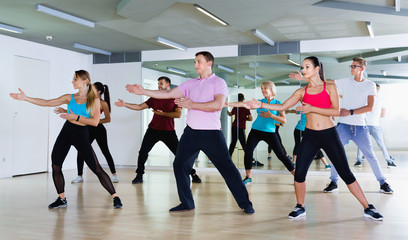 Men women performing modern dance in fitness studio