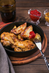 Fried chicken legs with fried potatoes in pan