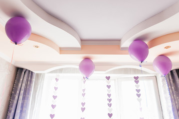 Purple balloons against the window and the ceiling, a holiday home, selective focus