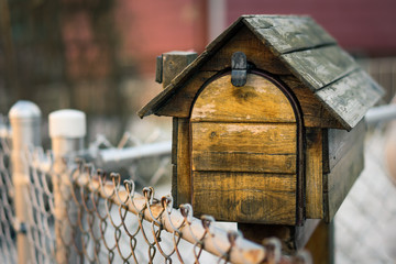 mailbox in the shape of a log cabin behind chain link fence