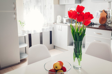 Modern kitchen design. Interior of white and silver kitchen decorated with flowers. Cozy apartment