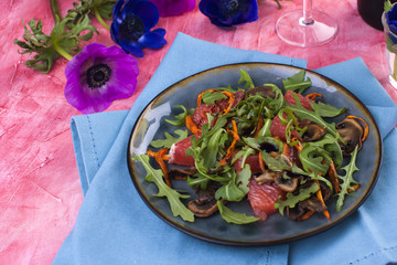 salad with arugula and salmon, dressed with sauce and grapefruit. Romantic dinner and flowers. card. Pink background