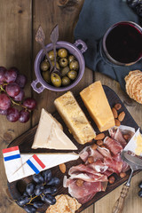 Different Dutch cheese. Ham, grapes, olives and snacks. Free space for text. Food and a glass of red wine