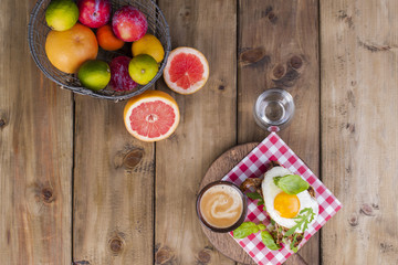 A cup of fragrant coffee and a glass of water. Toast with egg and salad and fruit for breakfast. Tasty and healthy food. Diet and vitamins. Good morning. Wooden background. View from above. Text
