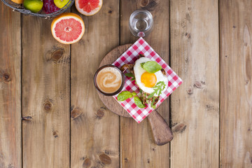 A cup of fragrant coffee and a glass of water. Toast with egg and salad for breakfast. Tasty and healthy food. Diet and vitamins. Good morning. Wooden background. View from above. Text