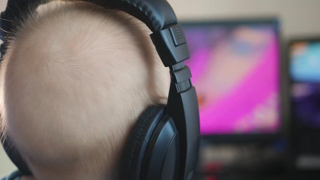 Baby boy in headphones playing the computer game. The concept of computer addiction, selective focus.