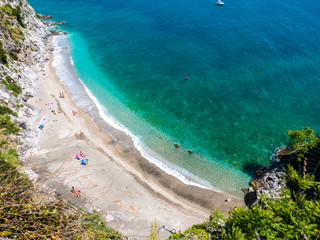Amalfi Coast, Naples, Italy. Abstract aerial view of a secret beach, with white pebbles and turquoise sea water, surrounded by green trees and almost desert beach with no people.