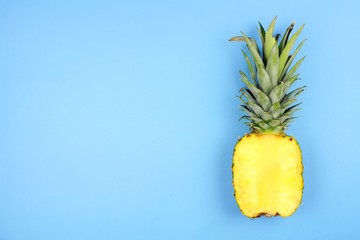 Half cut juicy pineapple on a pastel blue background. Minimal summer concept. Copy space.