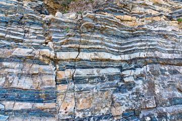 Compressed rock layers formation in various colors and thicknesses, on south central coast of the  Mediterranean island Crete, Greece. Nature and Geological science concept