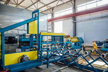 Thermal insulation sandwich panel production line. Roller conveyor, insulation panel assembly machine in workshop