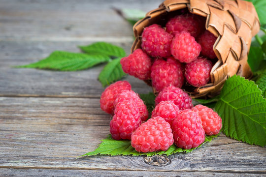 Raspberries in a basket on a wooden background.
