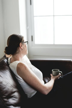 Woman sipping a drink sitting on a counch