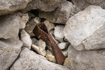 Old rusty ax without handle lying between rocks
