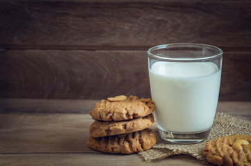 Glass of milk and peanut cookies on wooden background