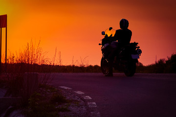 silhouette of rider on a motorbike admiring sunset - space for your text