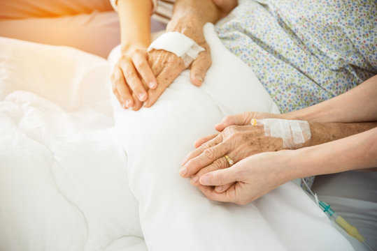 Daughter and nurse holding senior female patient's hands